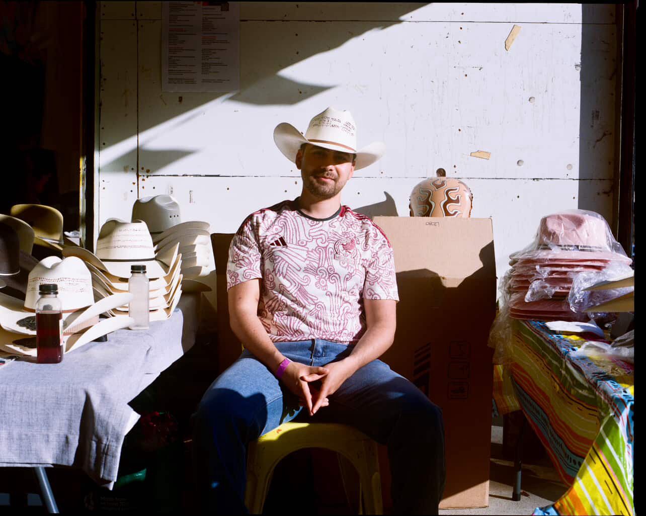 Man sitting in a room with various items including hats and boxes